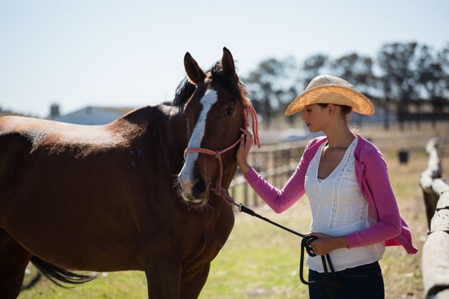 Young woman standing with horse at ranch on sunny day