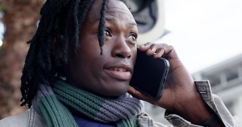 African American Man Talking on Phone Outdoors Wearing Knit Scarf and Light Jacket