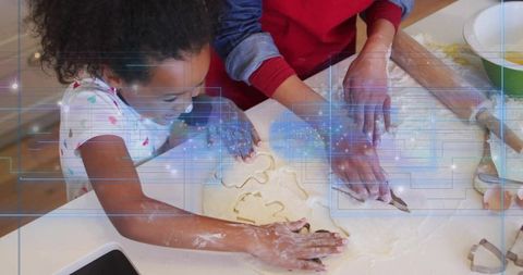 Mother guiding child pressing cookie cutters on flour-dusted countertop for holiday baking