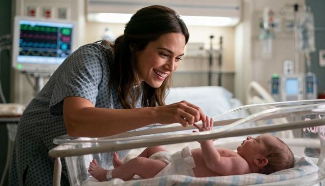 New mother bonding with newborn in maternity bassinet smiling while touching tiny hand