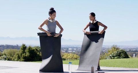 Friends Rolling Yoga Mats on Scenic Terrace