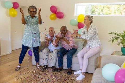 Joyful Senior Friends Celebrating with Confetti Indoors