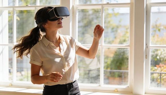 Woman wearing vr headset reaching and exploring sunlit room virtual reality experience