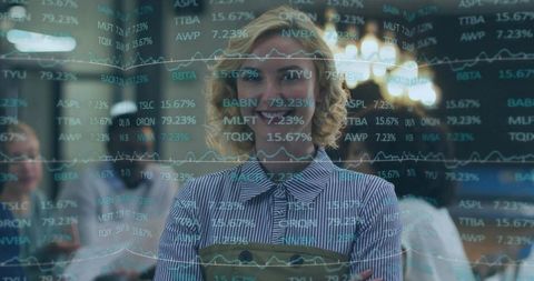 Confident businesswoman standing behind glass displaying stock tickers and financial graphs