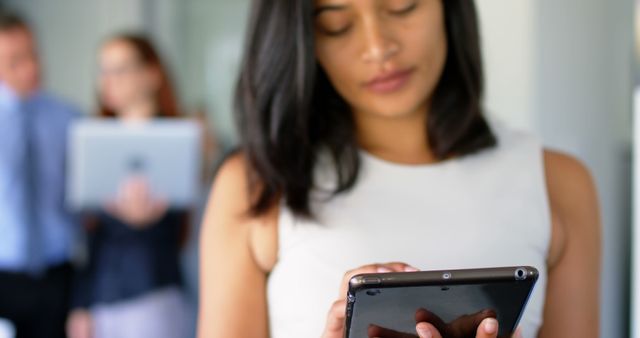 Businesswoman Using Tablet in Office, Colleagues in Background - Download Free Stock Images Pikwizard.com