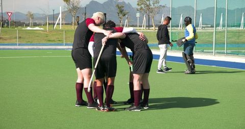 Field hockey team huddling on artificial turf before match