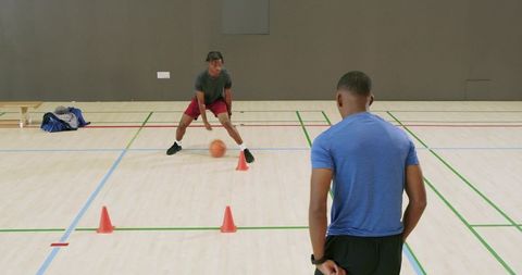 African american teen dribbling through cones in indoor basketball agility drill