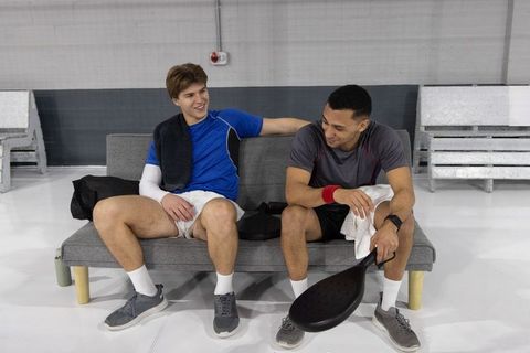Teammates relaxing on sofa after paddle sport training, chatting, cooling down together