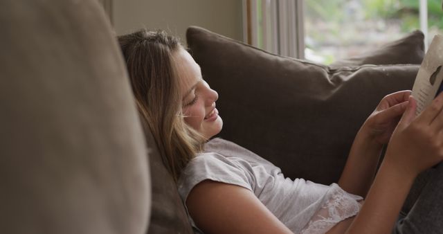 Girl Smiling While Reading on Comfortable Sofa - Download Free Stock Images Pikwizard.com