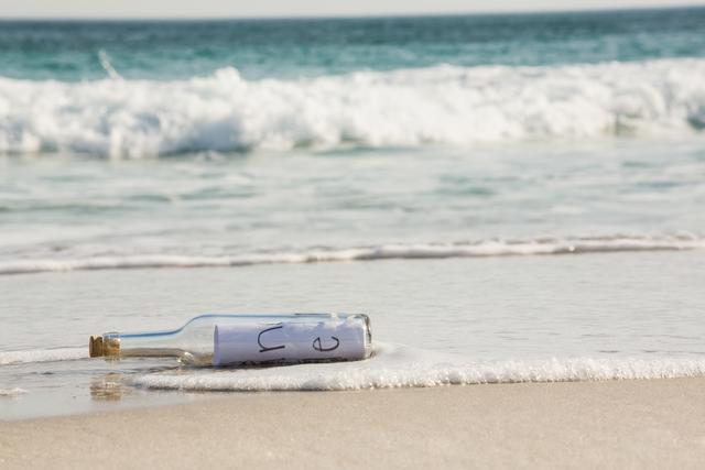 A glass bottle with a rolled message inside washes onto sandy beach near ocean waves. Ideal for concepts of mystery, adventure, communication, and hope. Suitable for travel blogs, inspirational content, and storytelling visuals.