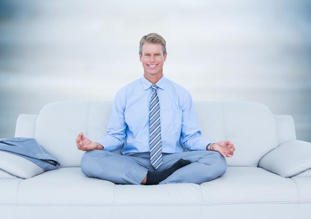 Depicts a businessman sitting in a meditative yoga pose on a couch. Dressed in a suit and tie, indicating a modern office environment. Ideal for promoting stress relief, mindfulness practices, and work-life balance in the corporate world. Useful for articles on workplace wellness and relaxation techniques.