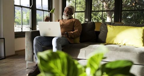 Senior man relaxing with laptop in cozy living room