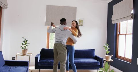 Happy Diverse Couple Dancing in Bright Living Room