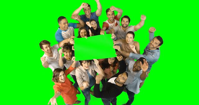 Team of excited business executives holding green placard against green screen