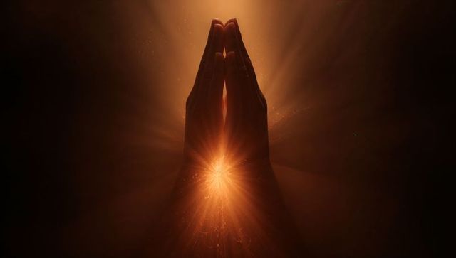 Praying hands radiating warm starburst light halo with particle glow