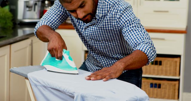 Man Ironing Clothes in Modern Kitchen - Download Free Stock Images Pikwizard.com