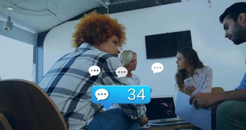 Creative team collaborating around laptop and mobile devices with chat notification badge
