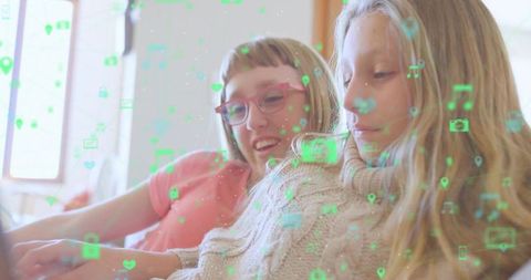 Girls on sofa engaging with floating digital icons