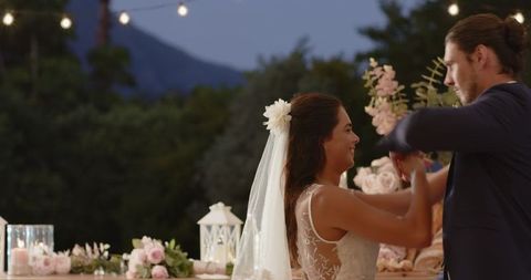 Newlywed couple dancing under twinkling outdoor lights at wedding reception