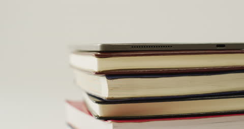 Stack of Books with Tablet on Top Highlighting Modern Learning