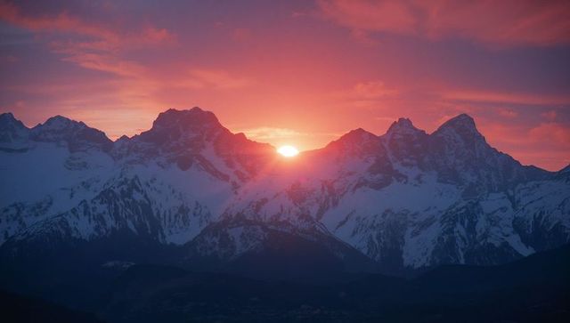 Serene alpine sunrise over snow-covered mountain peaks