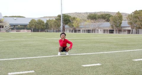 Youthful boy on school turf field embracing outdoor recreation