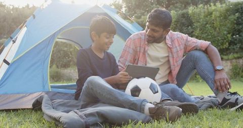 Father and Son Bonding with Tablet and Soccer Ball Outdoors