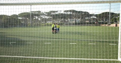 Soccer Team Strategizing Under Bright Sky on Green Field