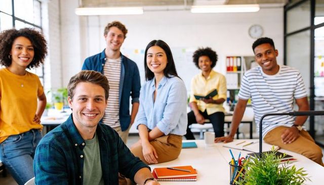 Diverse young team collaborating in bright modern office, smiling creative startup coworkers