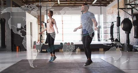 Pair performing high-intensity jump rope cardio in boxing gym with world map overlay