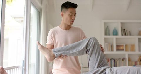 Physiotherapist assisting senior patient with muscle stretching