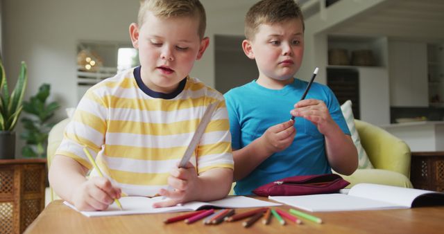 Caucasian boy with his brother sitting at table and learning at home - Download Free Stock Photos Pikwizard.com