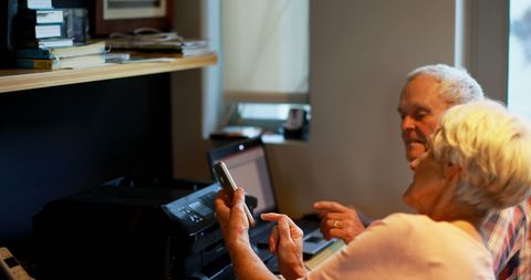 Senior couple exploring smartphone technology with enthusiasm