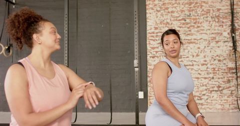 Multiracial women checking smartwatches after training in urban gym with brick wall