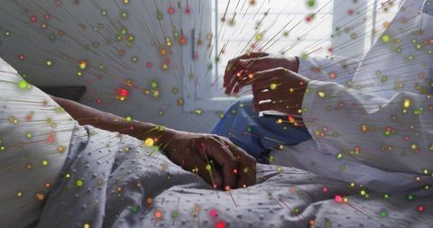 Clinician reaching hand to patient on bed by window with warm light and particle overlay
