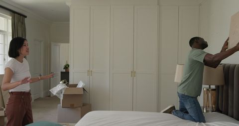 Couple arranging artwork in new home amid moving boxes
