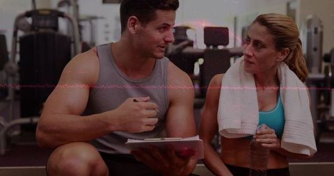 Personal trainer reviewing workout plan with female client during gym coaching session
