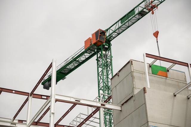 Crane operating at construction site with steel and concrete structures visible. Ideal for illustrating themes related to construction, urban development, engineering projects, and industrial machinery. Useful for articles, presentations, and marketing materials in the construction and real estate industries.