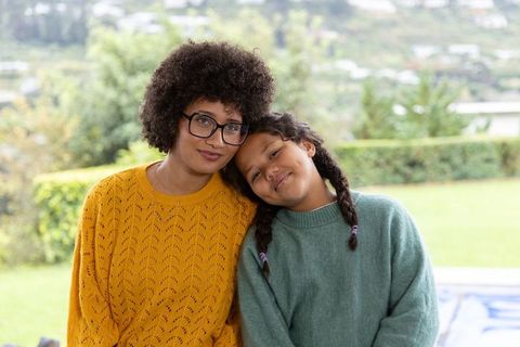 African-american mother and teen daughter sitting in backyard wearing cozy knit sweaters