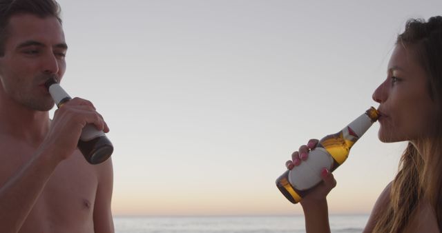 Young couple enjoying beers on beach at sunset - Download Free Stock Images Pikwizard.com