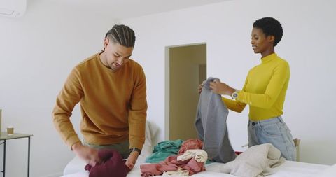 Diverse couple folding laundry in modern workspace
