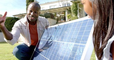 Black father kneeling teaching child about solar panel and renewable energy math