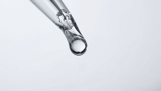Suspending single droplet from glass dropper with crystal-clear reflections and refraction