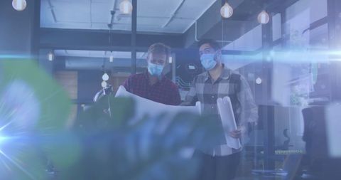 Office work in pandemic with masked colleagues reviewing plans