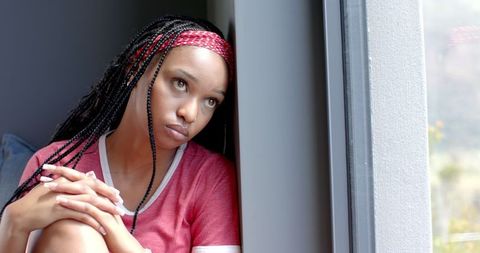 Contemplative african american female sitting by window