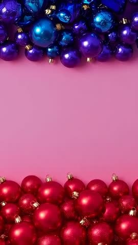 Moving camera reframing bauble clusters on pink background revealing glossy blue and red ornaments