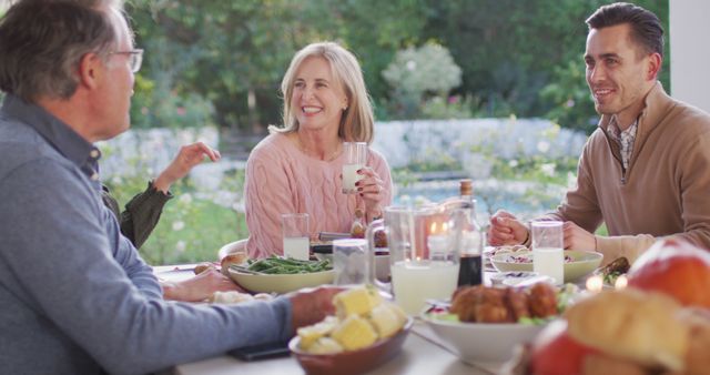 Image of happy caucasian parents, daughter and grandparents talking at outdoor dinner table. Family, domestic life and togetherness concept digitally generated image.