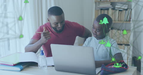 Father Assisting Son with Homework Using Laptop at Home