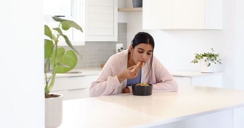 Woman Eating with Chopsticks in Minimalist Kitchen Interior