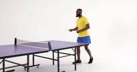 Man Playing Table Tennis Enthusiastically in Modern Studio